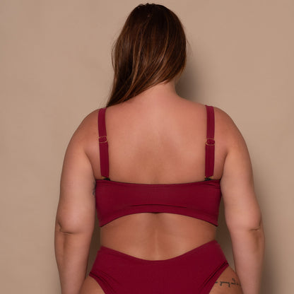 plussize woman wearing a pomegranate red bikini  against a beige background