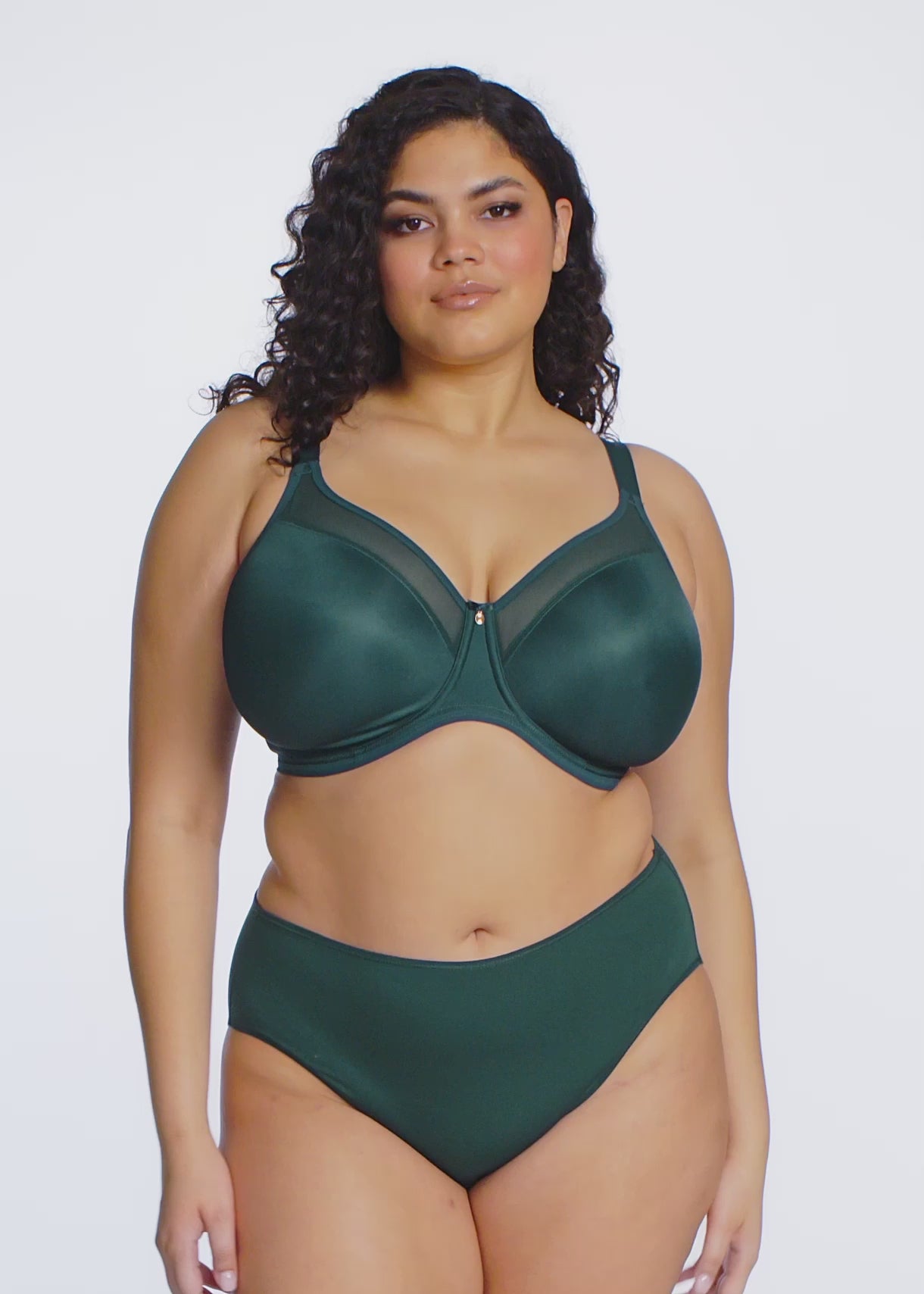 curvy woman wearing deep green lingerie against a white background