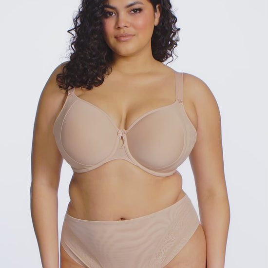 Curvy woman wearing beige lingerie against a white background