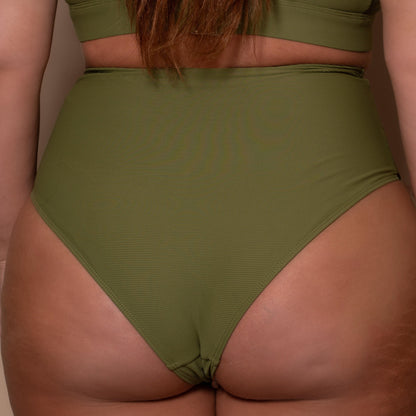 plussize woman wearing a khaki green bikini  against a beige background